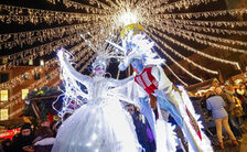 Leuchtende Walking-Acts unter dem Lichterhimmel des Weihnachtsmarktes